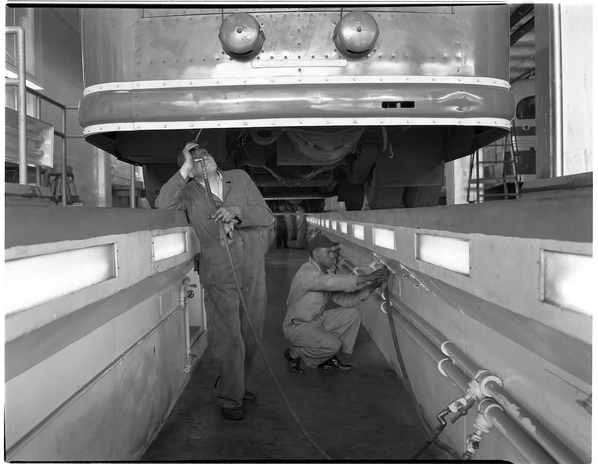 image of men working under a bus in maintenance pits