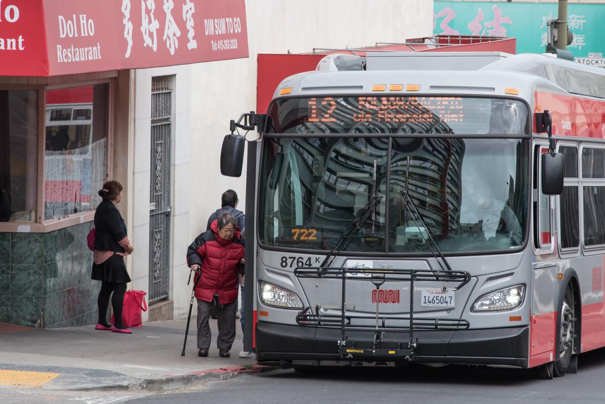A person using a cane and boarding the 12 Fulton bus.