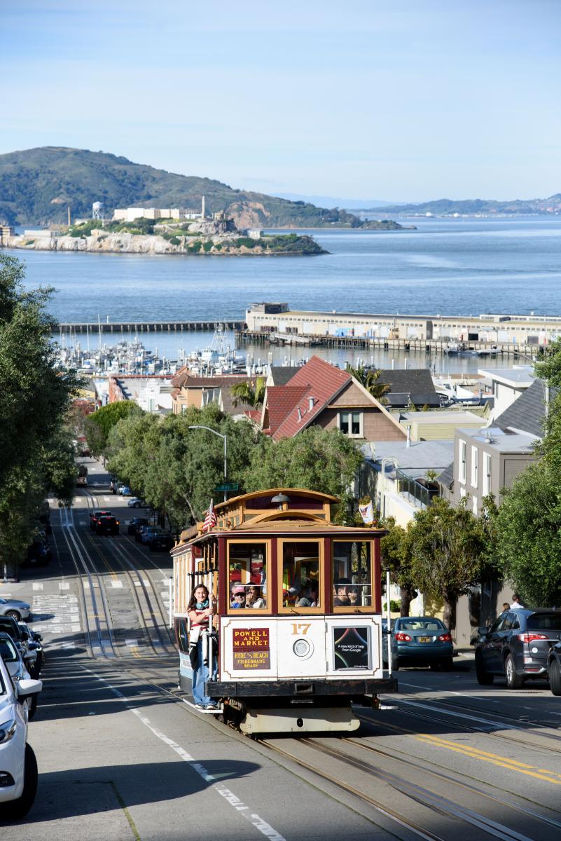 A cable car on a street with trees.