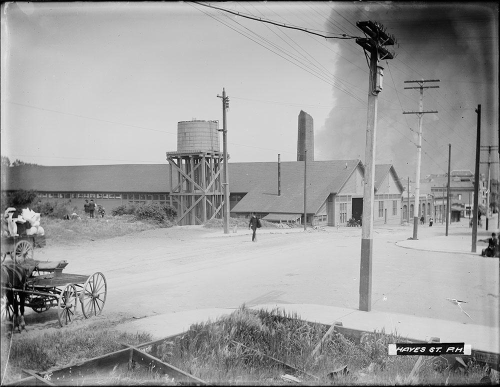 A person walking near a building with smoke behind it 