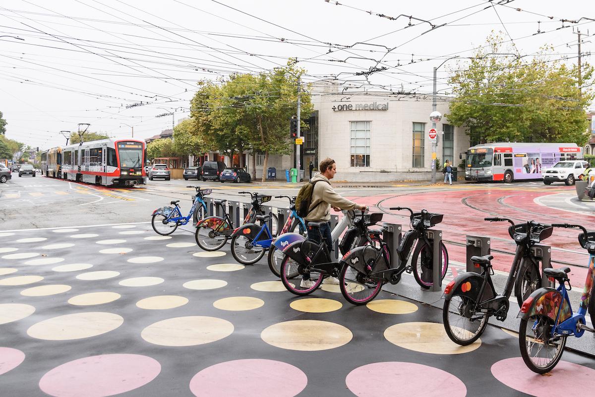 A row of bikes near a train with a person holding one bike.  