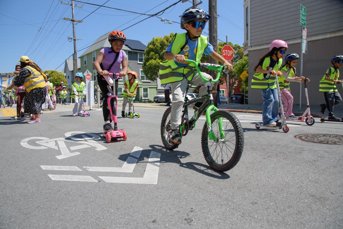 Kids cycling and scootering wearing helmets and high visibility vests