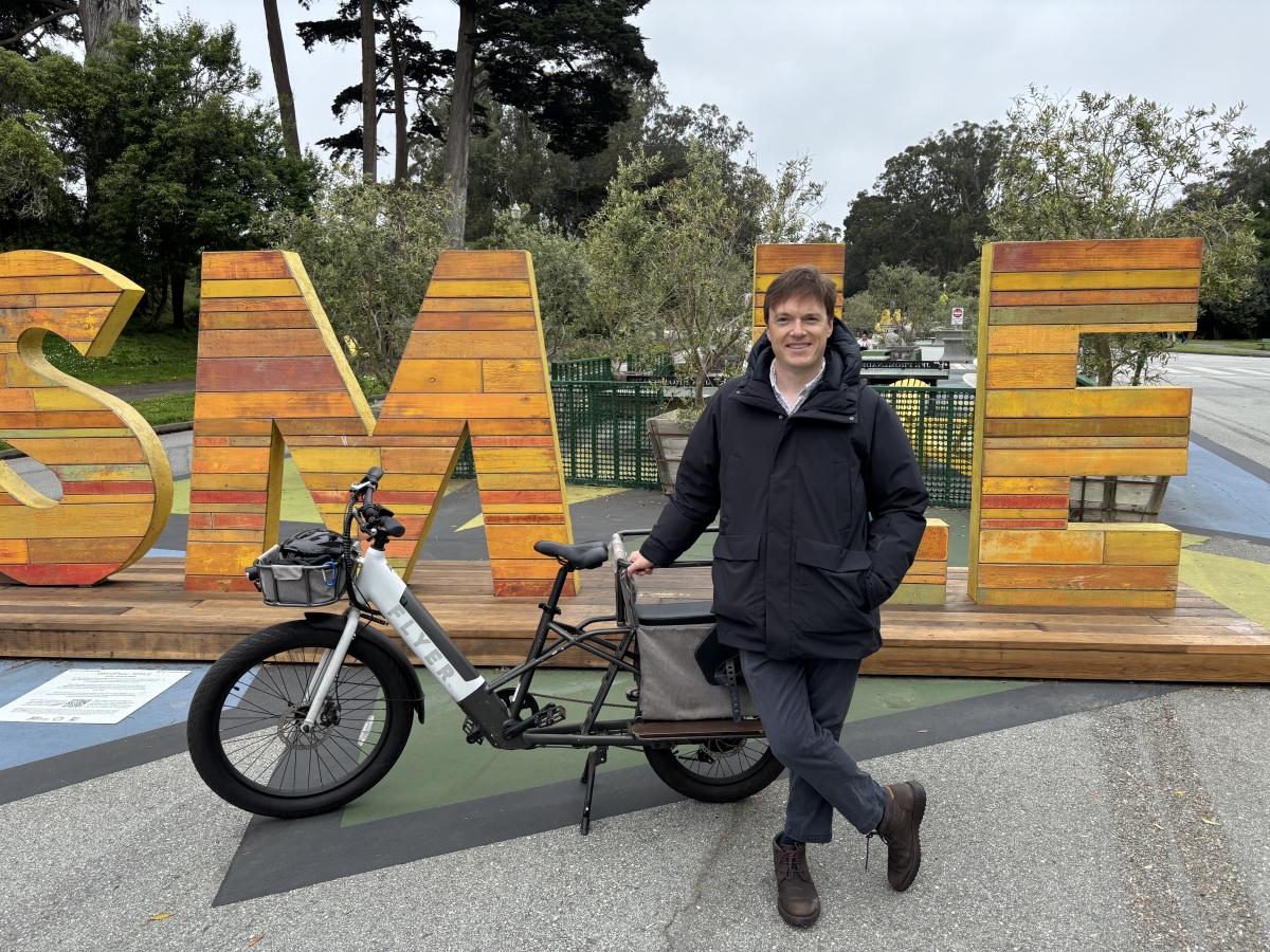 A person with a bike in front of large letters made of wood. 