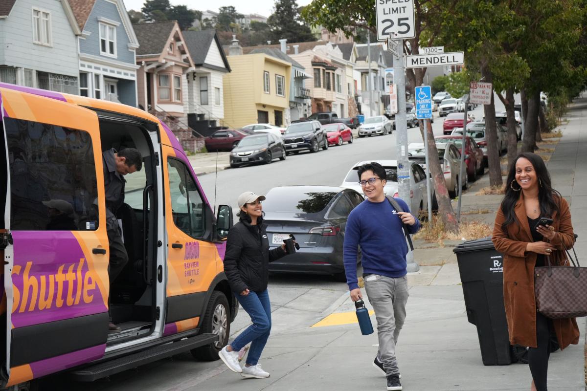 People getting out of a van at the curb.