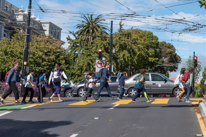Children and adults crossing the street at a crosswalk.