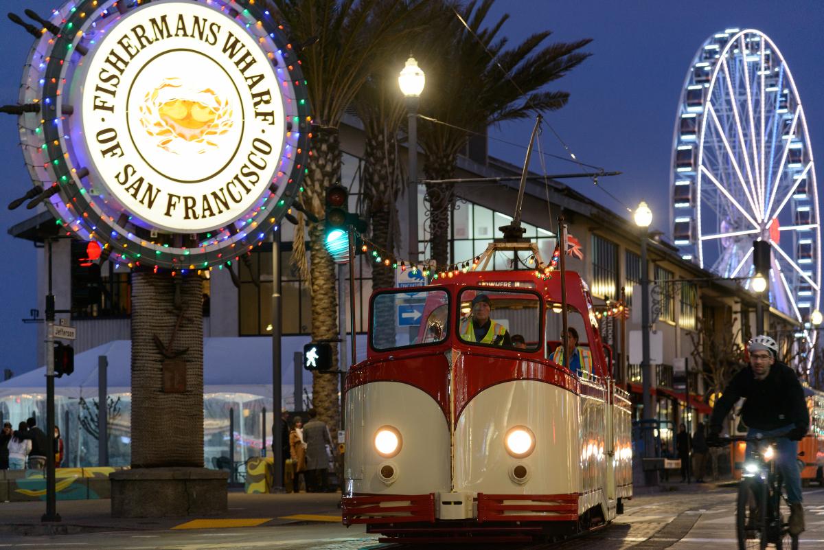 The boat tram streetcar next to a sign reading “Fisherman’s Wharf of San Francisco.