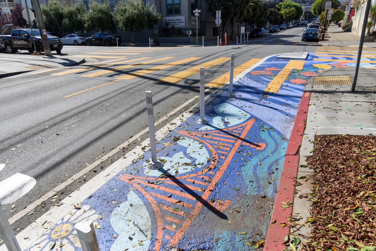 Mural painted on a street next to a red curb. 