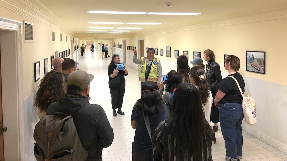 People standing in a hallway with photos on the walls. 