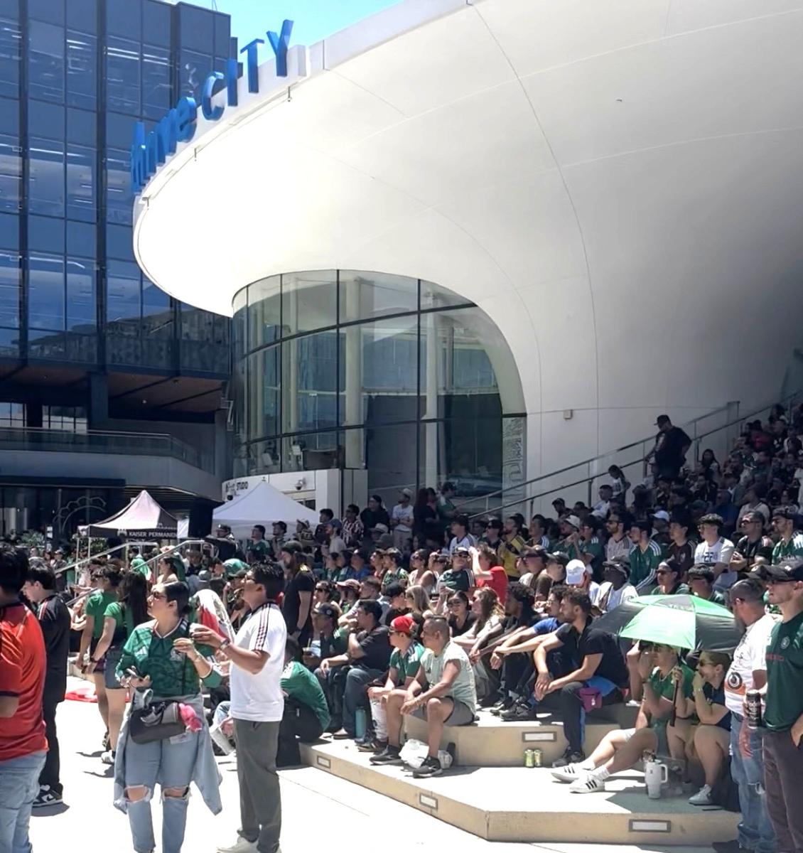 People sitting and standing outside on a plaza