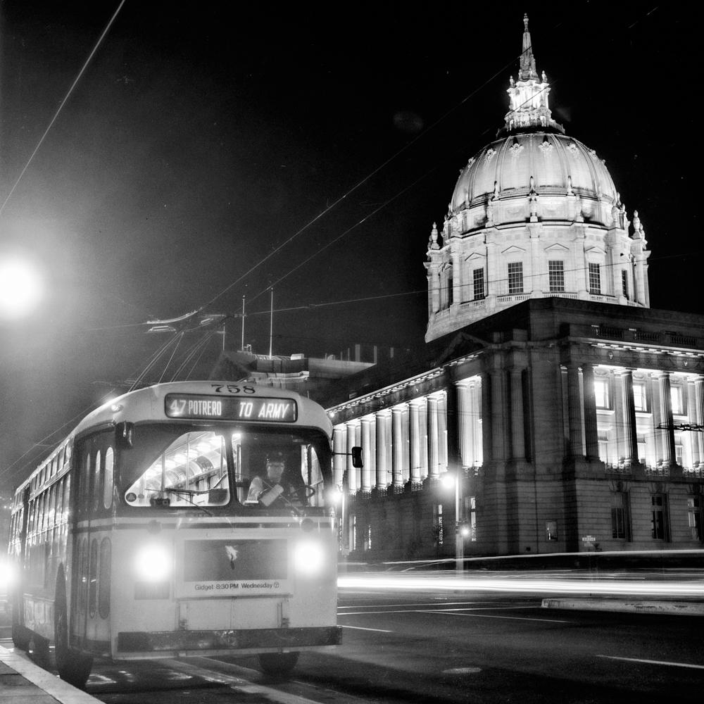 A bus on a street in front of a large civic building