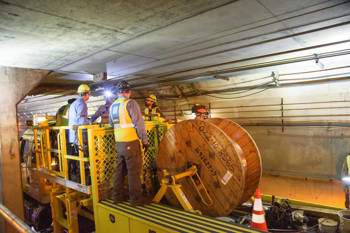 Workers in a tunnel inspecting overhead lines.