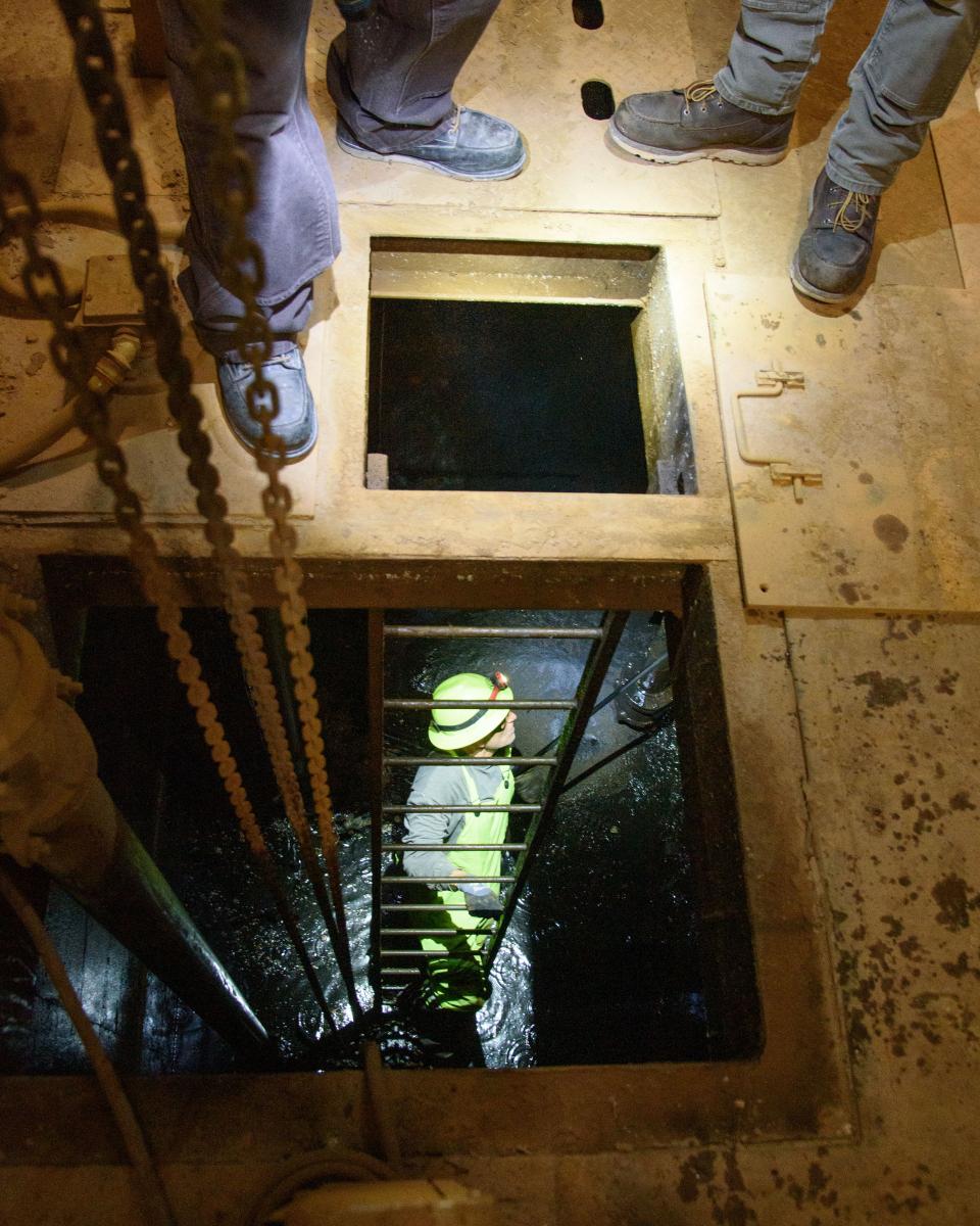  Person on a ladder in a hole underneath a wooden floor.    