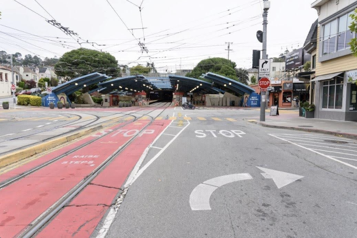 A red transit lane leads into a train station