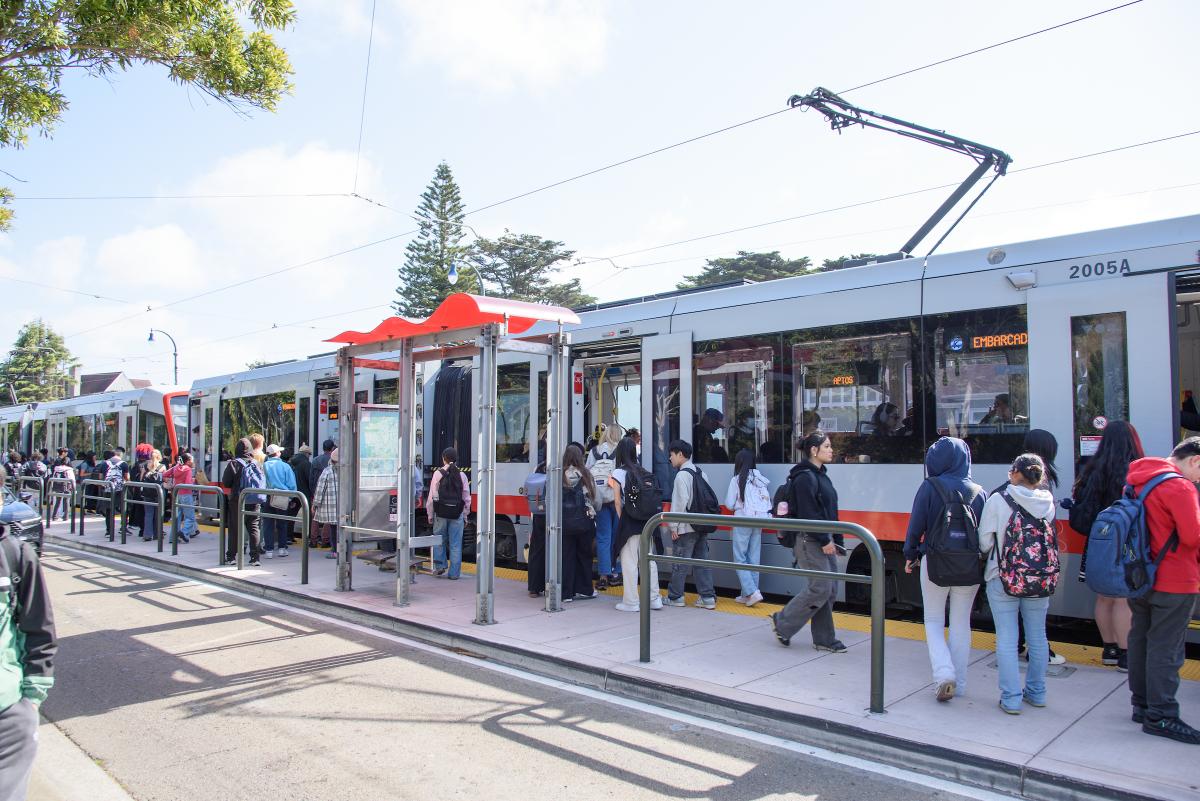 Young people outside of a light-rail vehicle.