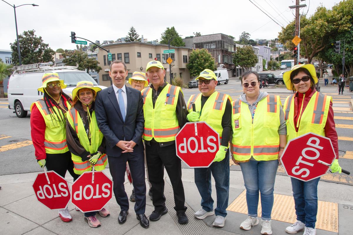 Crossing guards smile for a photo with Mayor Daniel Lurie.
