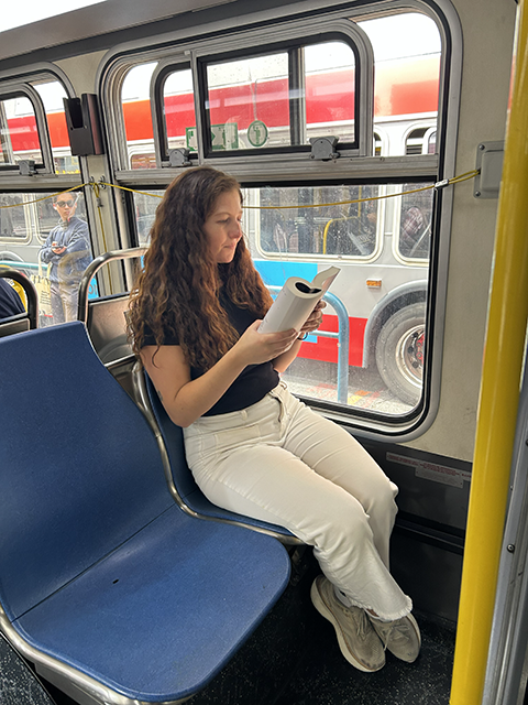 A person reading while riding a Muni bus.