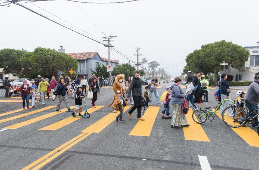Parents and children walking in a crosswalk.