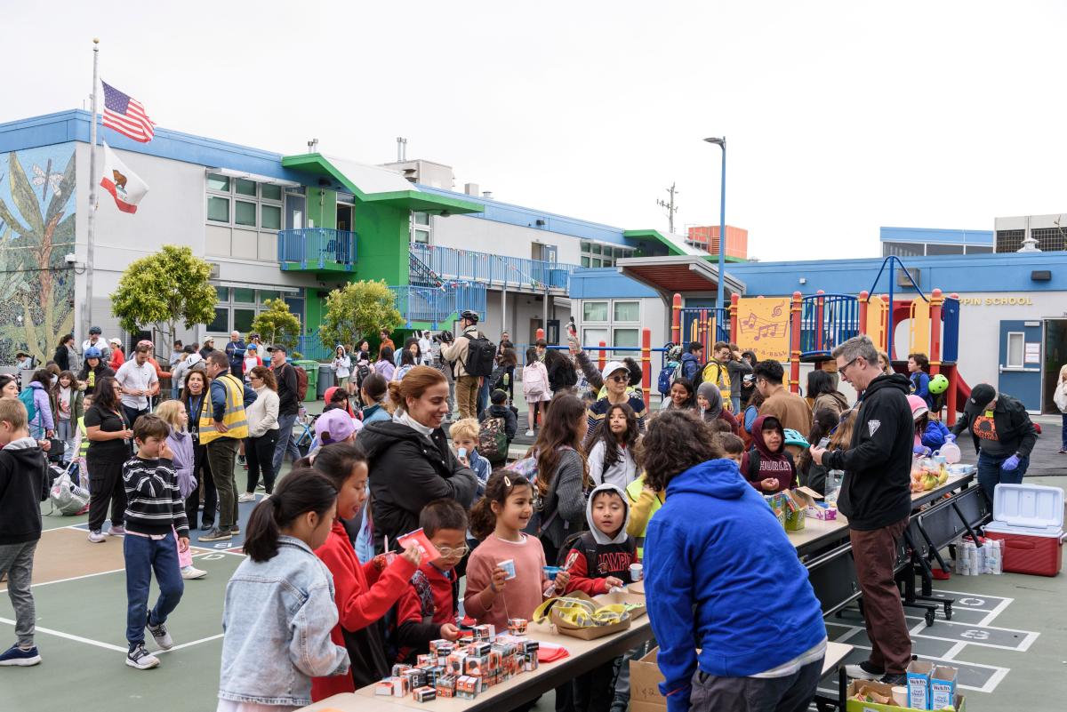 Students and caregivers gather near a table with activities for a school event.