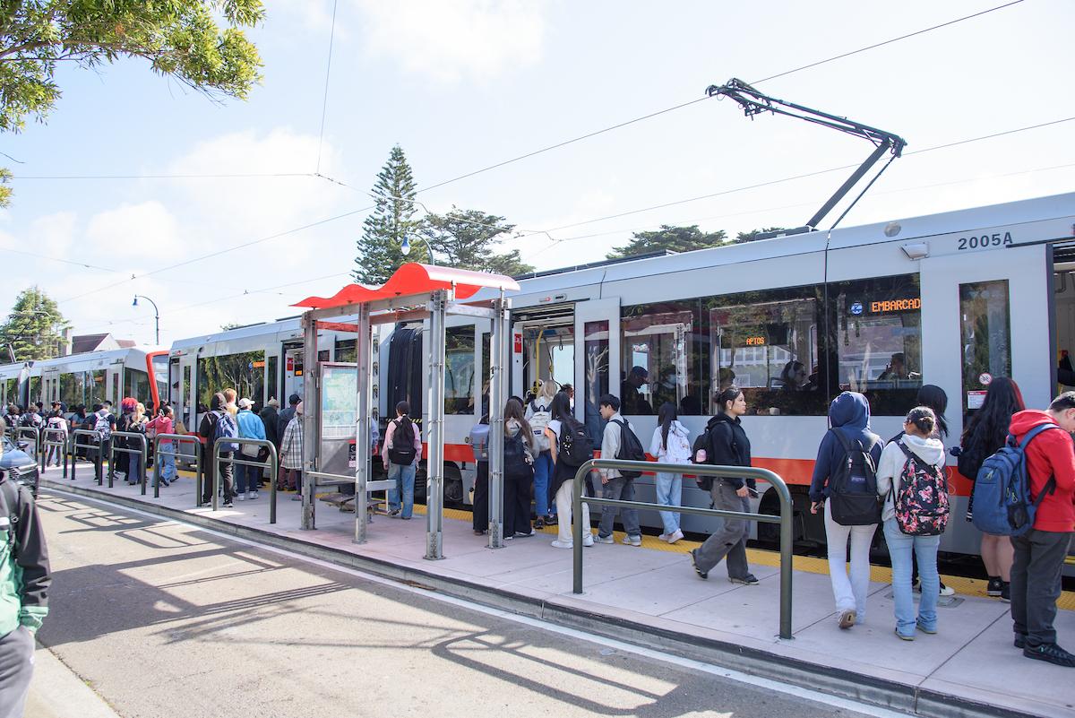 People standing and walking near a transit train at a stop