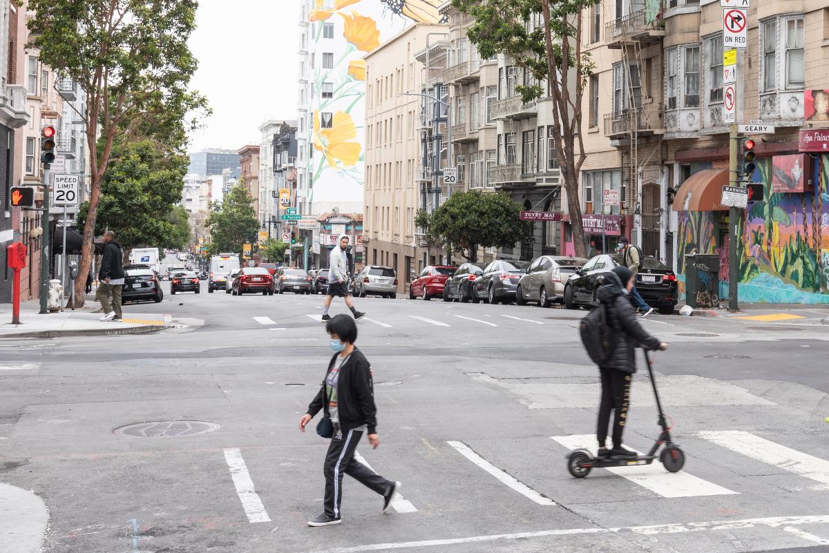  One person walking and another person on a scooter in a crosswalk