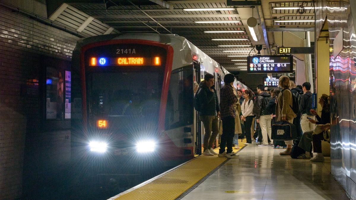 People board a public transit train in a station.