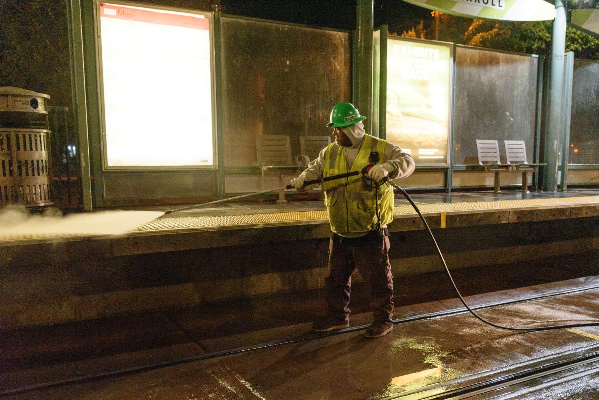 A man power washes a transit platform.