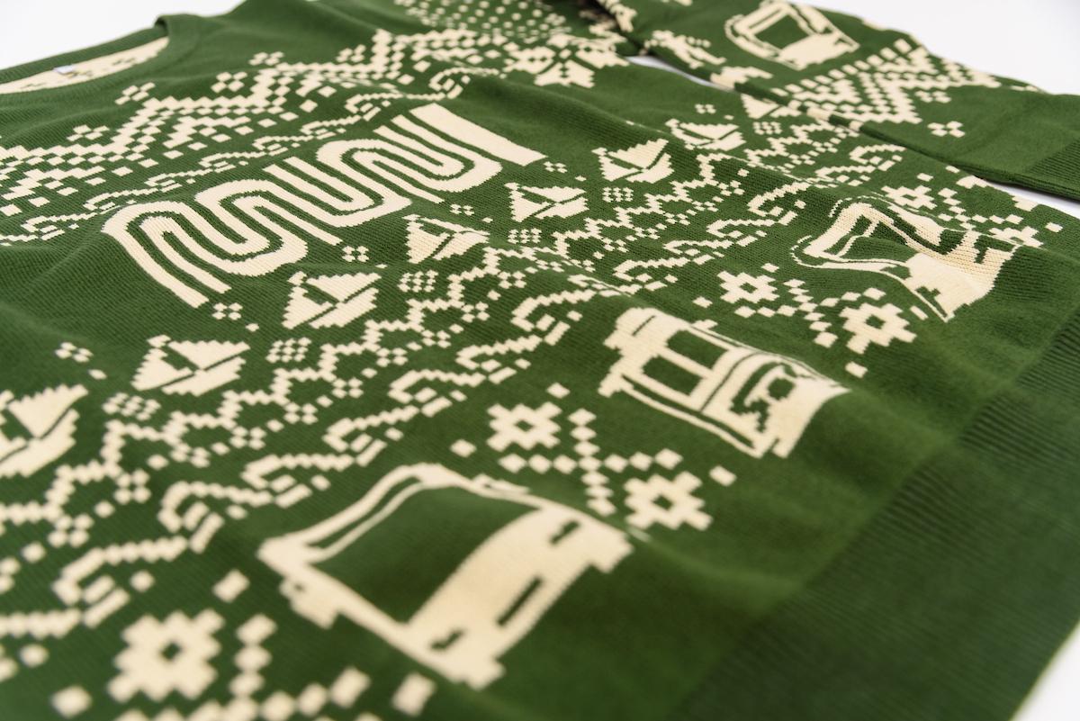 A green sweater with cream lettering and graphics on it.
