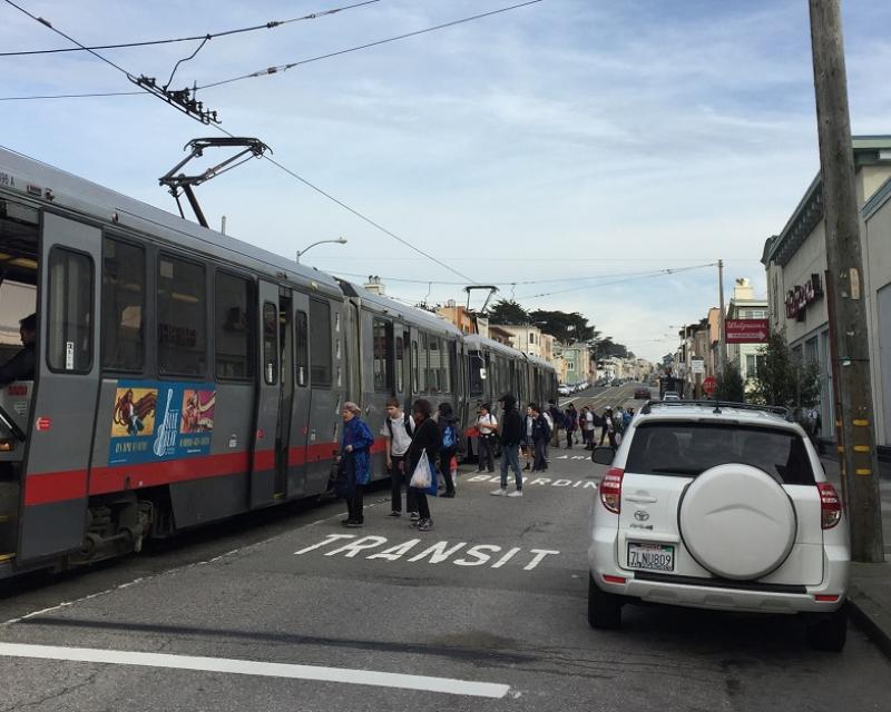 People on Taraval Street board a stopped Muni train