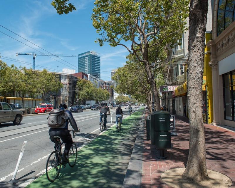 Bike lane at road-level, with green-painted pavement and plastic posts separating it from vehicle traffic.