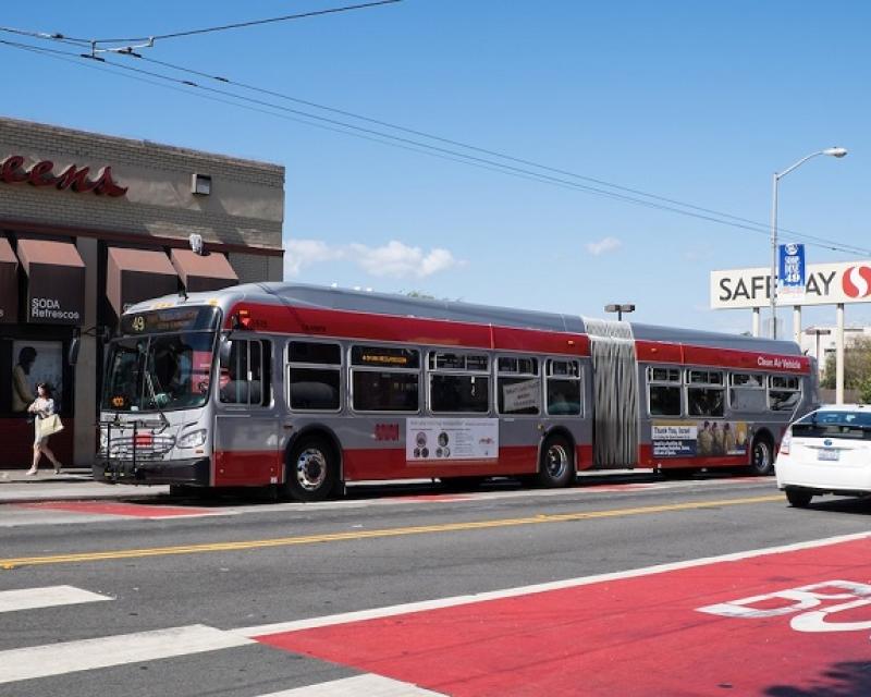 A Muni bus travels down a red transit-only lane on Mission Street at 30th Street as cars travel in the adjacent traffic lanes.