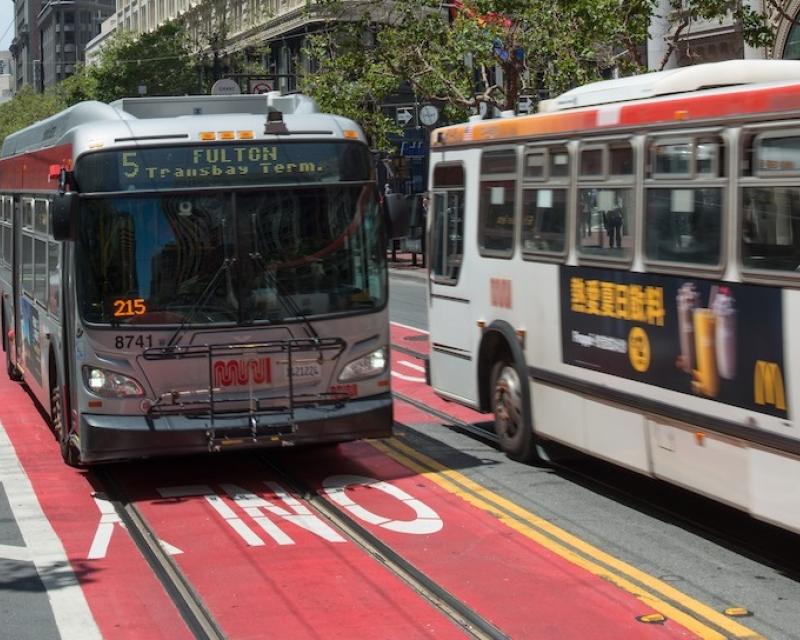Muni buses drive down red-colored transit-only lanes on Market Street.