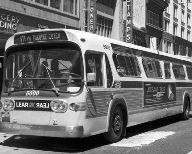 Black and white photo showing a GMC brand bus on Market Street near Sansome on August 23, 1972.  This bus is outfitted with a Lear steam turbine engine for testing by Muni.