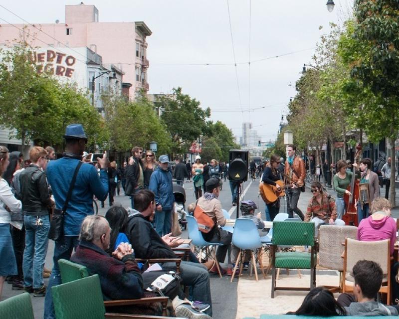 Image: People watching a musical performance on a car-free roadway at Sunday Streets on Valencia Street.