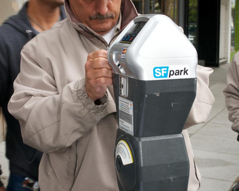 Man in baseball hat installing a new parking meter 