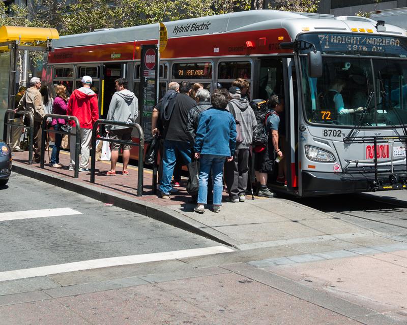 people boarding muni bus from platform on market street