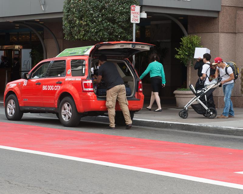 taxi driver loading passenger's luggage into red taxi cab on O'farrell street