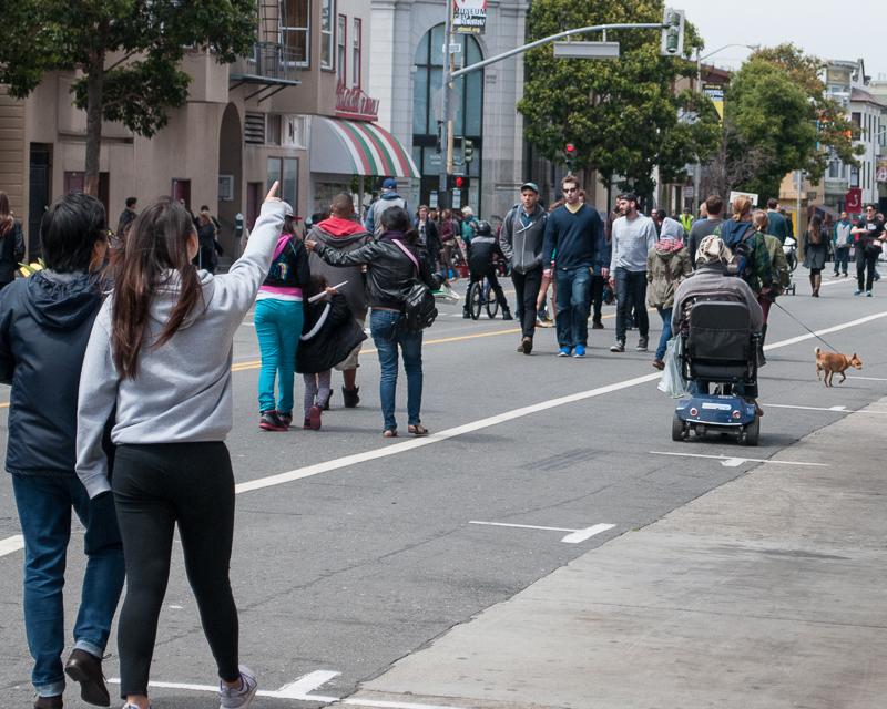 people walking down a closed Valencia street during Sunday Streets street fair