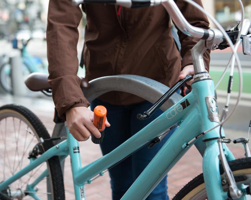 Sidewalk bike rack with teal bike and woman locking it