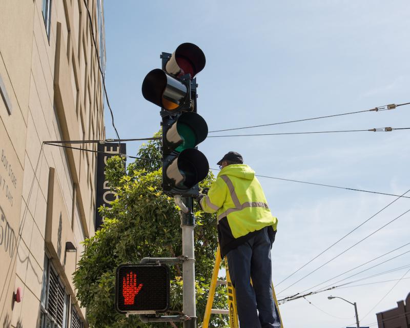 Worker in yellow jacket working on traffic light