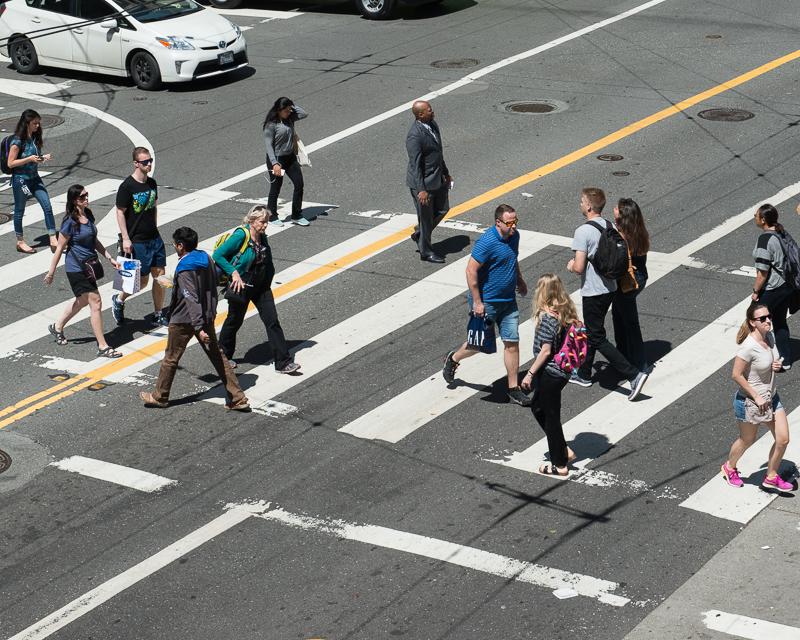 group of people crossing street in striped crosswalk