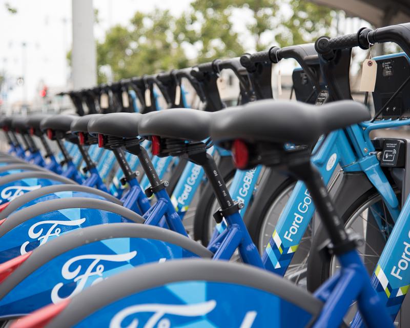 row of blue rental bicycles in ferry plaza