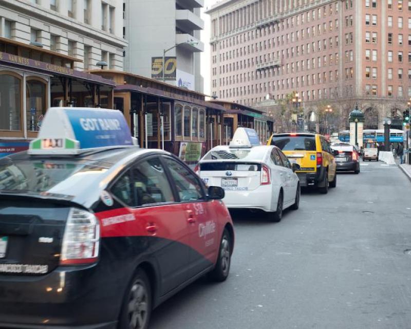 Taxis from various companies, lined up on California street alongside cable cars