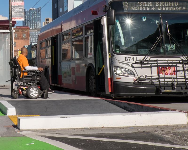 man in wheelchair waiting to board Muni bus