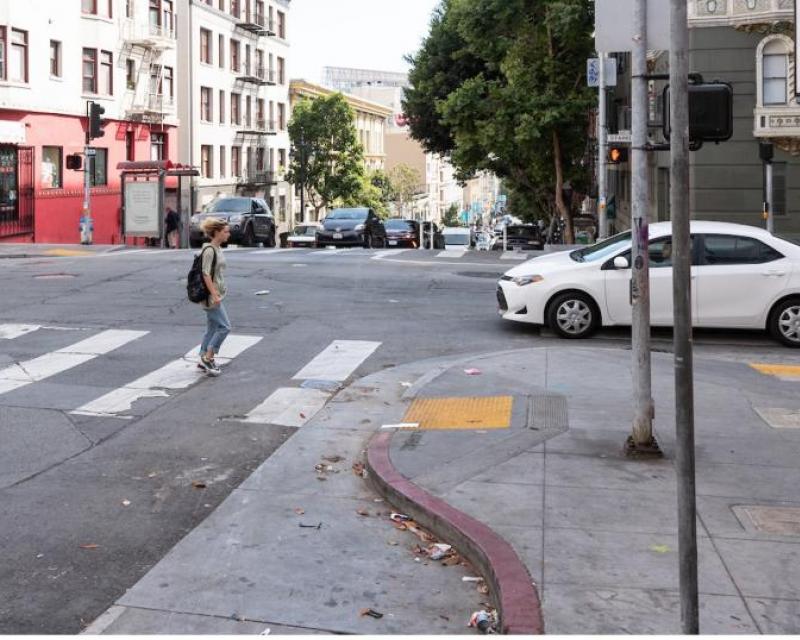 A bulb-out is shown extending the sidewalk at an intersection further into the street; a pedestrian crosses toward it