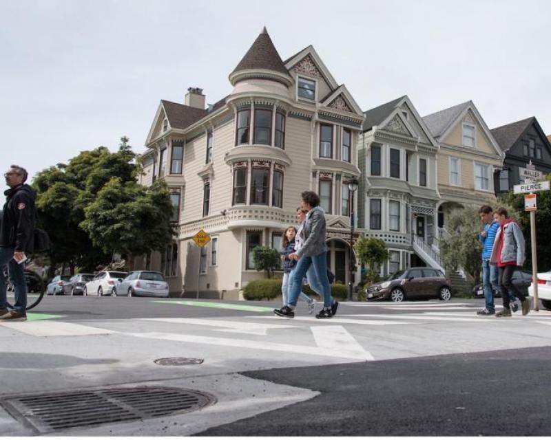 Pedestrians cross Waller and Pierce streets in a raised crosswalk