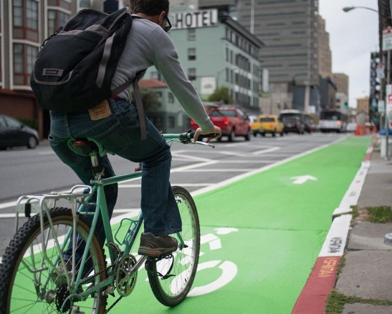 A man bikes on a parking-protected bike lane on 7th Street. 