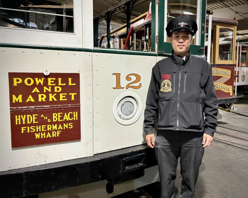 A cable car operator standing in front of a cable car.