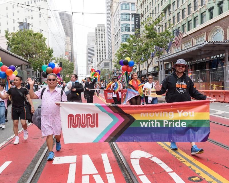 SFMTA staff holding banner and marching on Market Street during the SF Pride Parade