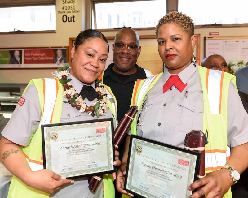 A photo of Annie Washington and Chanelle Smith, two of Muni’s newest cable car grips, holding up certificates of achievement.