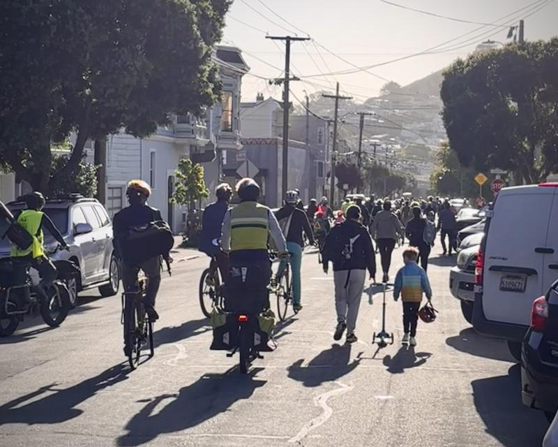 Adults and children on bikes and walking in the street
